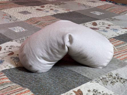 A Sachi Organics Buckwheat Neck Pillow on top of a quilt