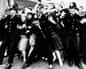Police officers link arms to hold back screaming, reaching Beatles fans