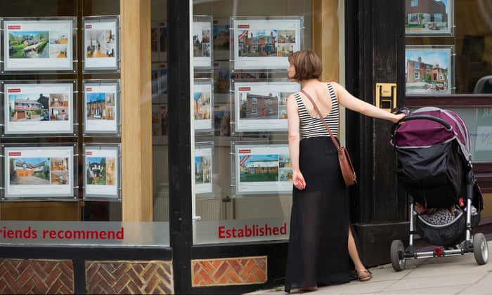 Woman with pushchair looking at houses in estate agent window