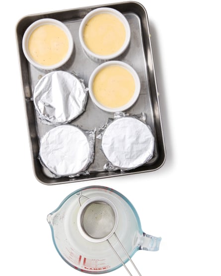 Custard-like liquid in ramekins, on a tray, next to a jug with a small sieve