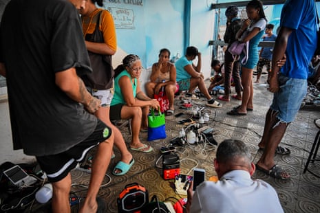 Residents of the town of El Cobre, in the city of Santiago de Cuba, charge their mobile phones after the passage of Hurricane Melissa, on October 29, 2025.