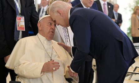 The pope sat as Joe Biden stands over him with his head touching the pope’s forehead