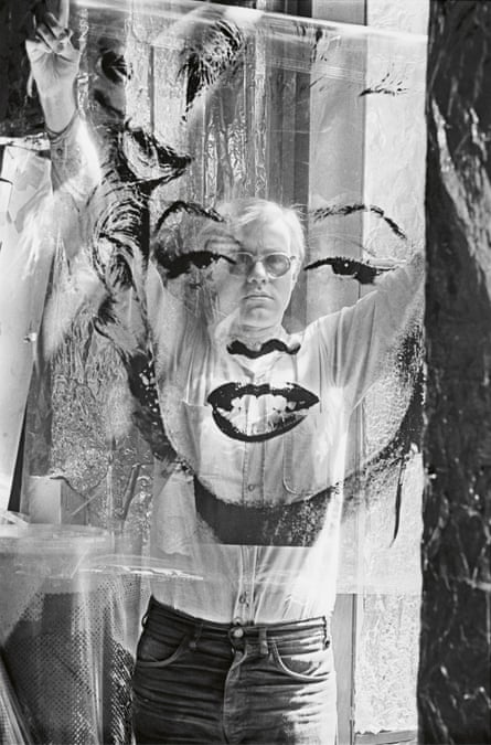 Andy Warhol holding a silkscreen acetate proof of his head of Marilyn Monroe in front of him