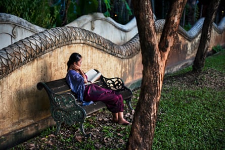 A female guest reads a book in the garden at Dhara Dhevi Hotel, Chiang Mai, Thailand