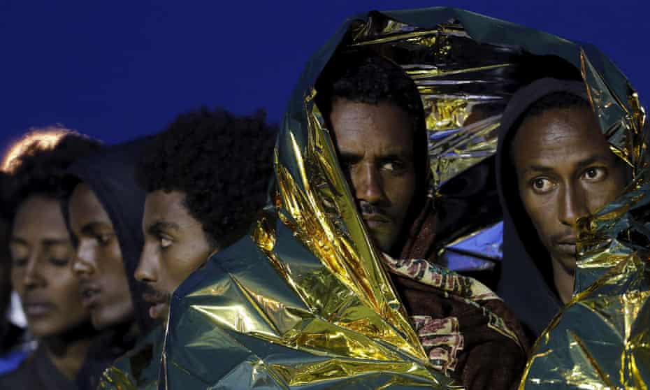 Migrants wrapped in thermal blankets queue to disembark from a rescue vessel in the Sicilian harbour of Augusta, Italy.