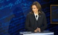 Kamala Harris, wearing a black jacket, folds her hands and looks to the side at a podium