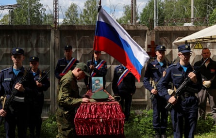 Soldiers stand next to a casket holding a Russian flag