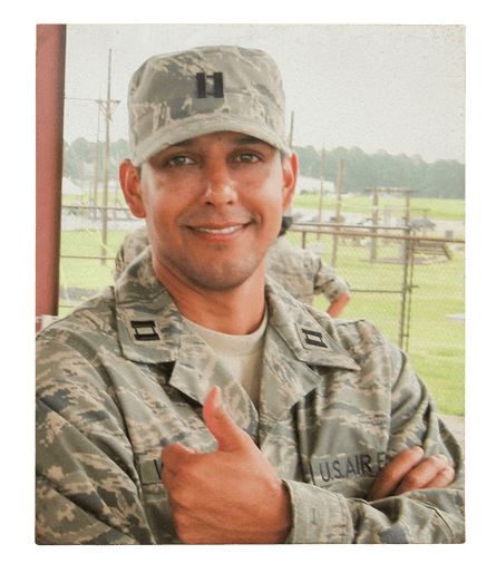 A young man in military uniform smiles and gives the thumbs-up.