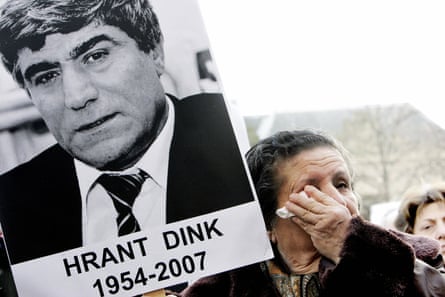 A woman on a march wipes her tears as she holds a portrait of Dink