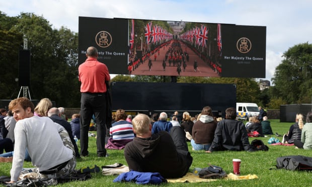 People watch the funeral of Queen Elizabeth on a large screen in Holyrood Park Edinburgh.
