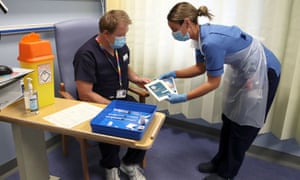 Deputy charge nurse Katie McIntosh shows leaflets to clinical lead Andrew Mencnarowski after giving him the first Covid vaccine in Scotland, at the Western general hospital in Edinburgh.