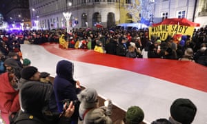 People in Warsaw hold a Polish flag at a protest against changes to the judiciary.