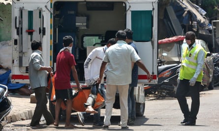 Health workers carry a man with suspected coronavirus into an ambulance in Dharavi.