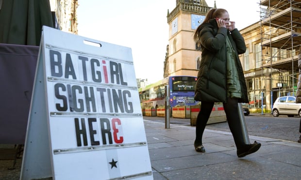 Un miembro del público pasa junto a un cartel en Glasgow, cerca de donde se filmaron partes de la película Batgirl en enero.