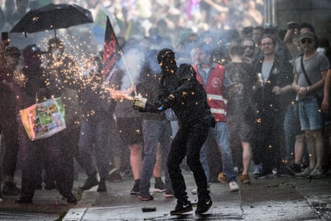 A protestor is sprayed with water from a water cannon as he sends fireworks to riot police during a May Day (Labour Day) rally, marking International Workers' Day, in Nantes.