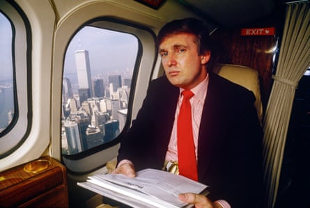 man in suit sits on plane holding papers, city skyline seen through window