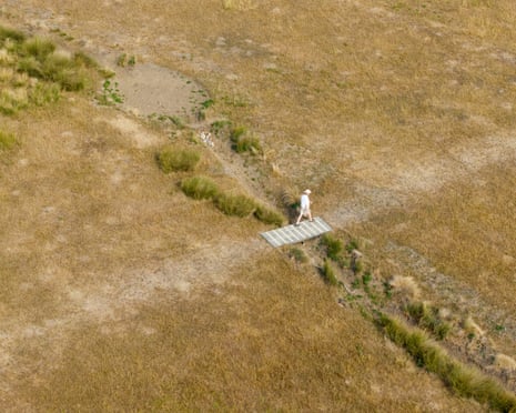 An aerial photograph shows a person walking over a dried up stream beside sun scorched grass at Richmond Park, south west London.