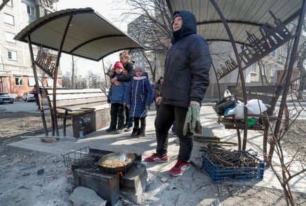With the electricity cut off, people prepare food over a makeshift stove in a yard during the siege of Mariupol.