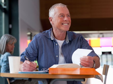 Smiling mature student thinking and sitting with textbook