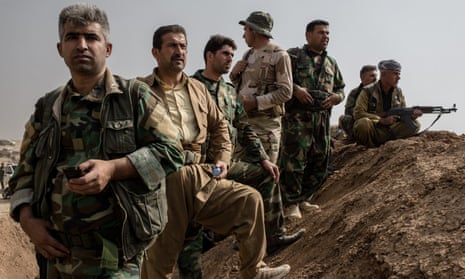 Peshmerga fighters stand on an earthen berm near Bashiqa