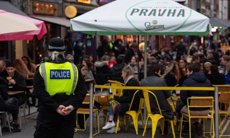 Officers monitor people seated outside bars and restaurants in Soho, London, last weekend.