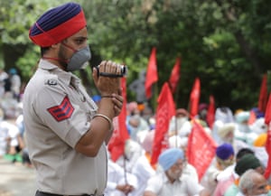 Amritsar, IndiaA police officer records Communist Party of India (CPI) activists as they take part in a protest about the government’s handling of coronovirus