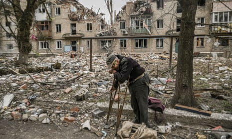 A man collects wood from debris in front of a destroyed apartment building after a strike in the city of Avdiivka, eastern Ukraine, on Saturday