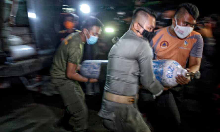 Officers unload oxygen tanks at an emergency oxygen station set up at a building in Bogor, West Java, Indonesia.