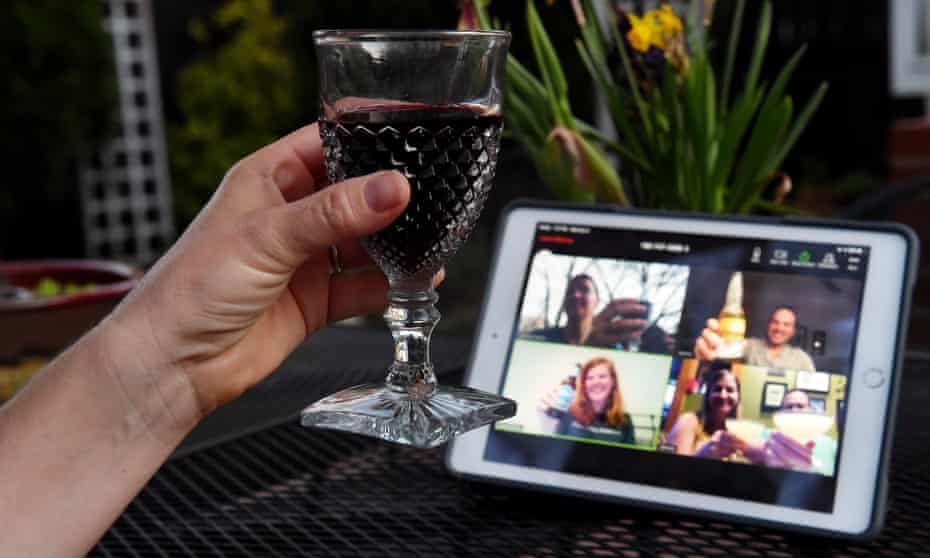 A woman lifts her glass and cheers with friends during a virtual happy hour amid the coronavirus  crisis