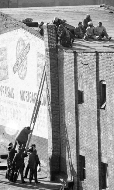 A man climbs up a ladder to people on the roof of a building