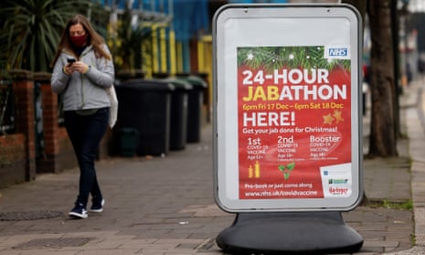 A pedestrian walks past a sign for a 24-hour vaccination centre in London.