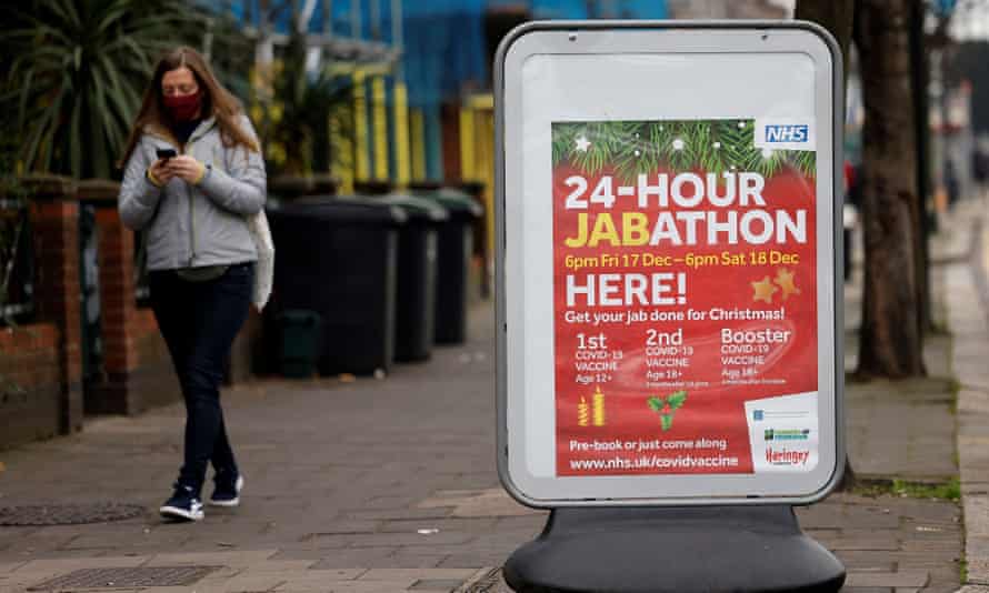 A pedestrian walks past a sign for a 24-hour vaccination centre in London. Photograph: Tolga Akmen/AFP/Getty Images