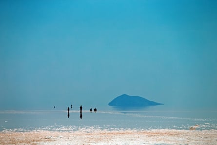 Distant figures stand and sit in the water