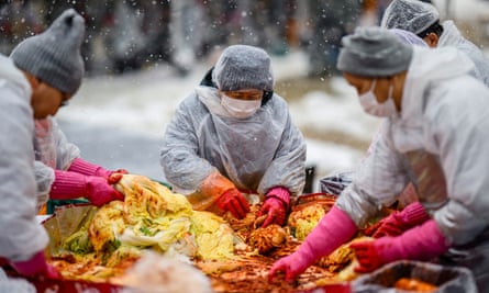 People prepare kimchi during a kimchi-making festival held amid snowfall at Jogyesa Temple in Seoul