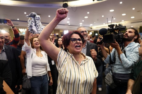 A woman pumps her fist in celebration among a crowd of Joint List supporters celebrating exit polls on 27 October 2026.