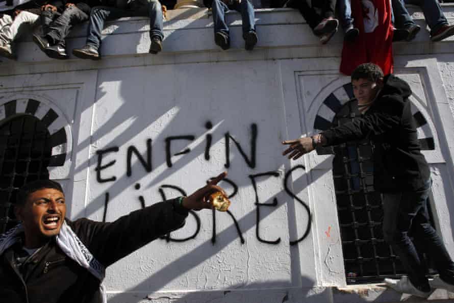Tunisian protestors pictured in January 2011 before a wall on which the words ‘Free at last’ are daubed