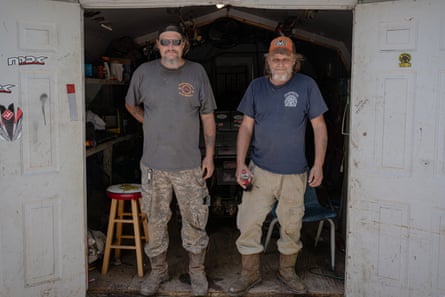 two men in t-shirts, pants and work boots standing in doorway