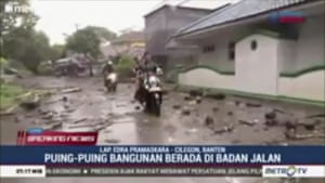 People ride motorbikes through water and debris-filled streets in Serang city.