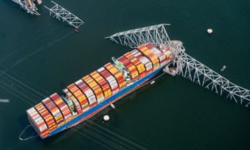 aerial photograph of huge container with collapsed bridge around it