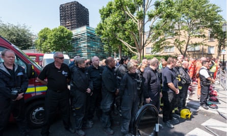 Members of the emergency services observe a minute’s silence near Grenfell Tower.