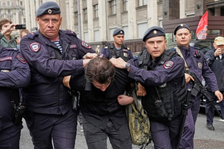 Police officers hold a man who is bent forward