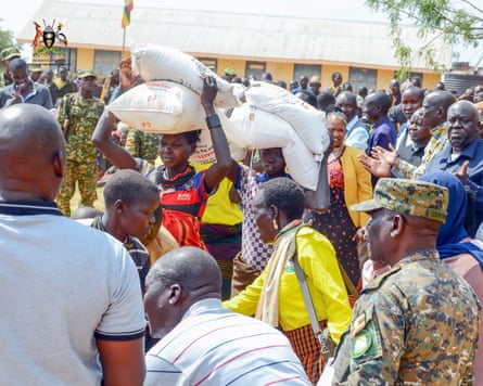 People carrying sacks of grain on their heads as others look on