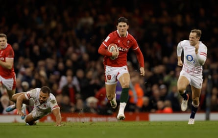 Wearing the red and white kit of Wales, Louis Rees-Zammit sprints clear to score to score during the 20-10 Six Nations defeat by England in 2023. Max Malins gives chase in white England kit