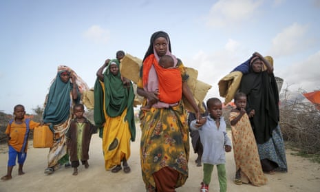 Somalis walking with their children arrive at a makeshift camp outside Mogadishu