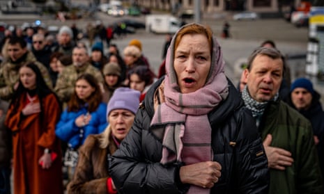 People sing the Ukrainian national anthem during a ceremony for slain Ukrainian volunteers.