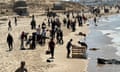 Palestinians gather on a beach as they collect aid dropped by an aeroplane