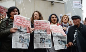 Protesters hold copies of the latest edition of Cumhuriyet after nine staff were arrested.