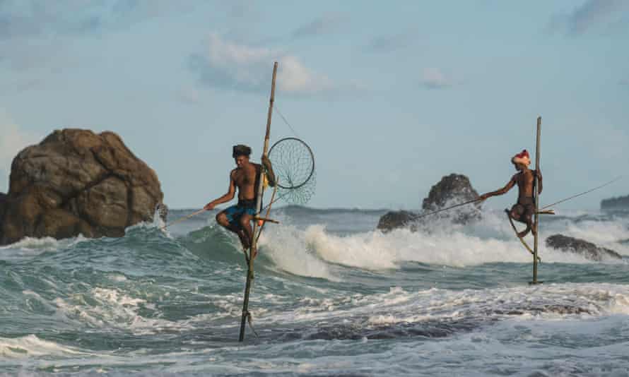 Sticking it out: stilt fishermen on the beach at Galle, Sri Lanka.