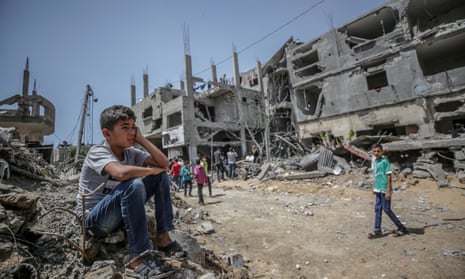 A Palestinian boy sits on the rubble of his house destroyed in an Israeli airstrike