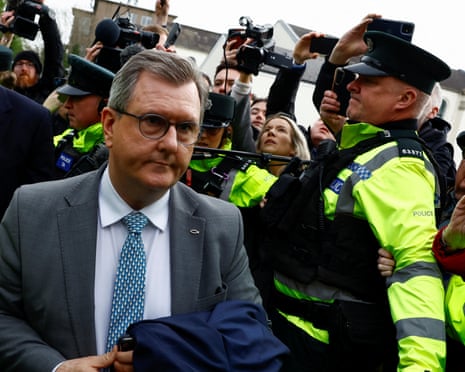 Police officers hi hi-vis jackets hold back journalists trying photograph and film Jeffrey Donaldson